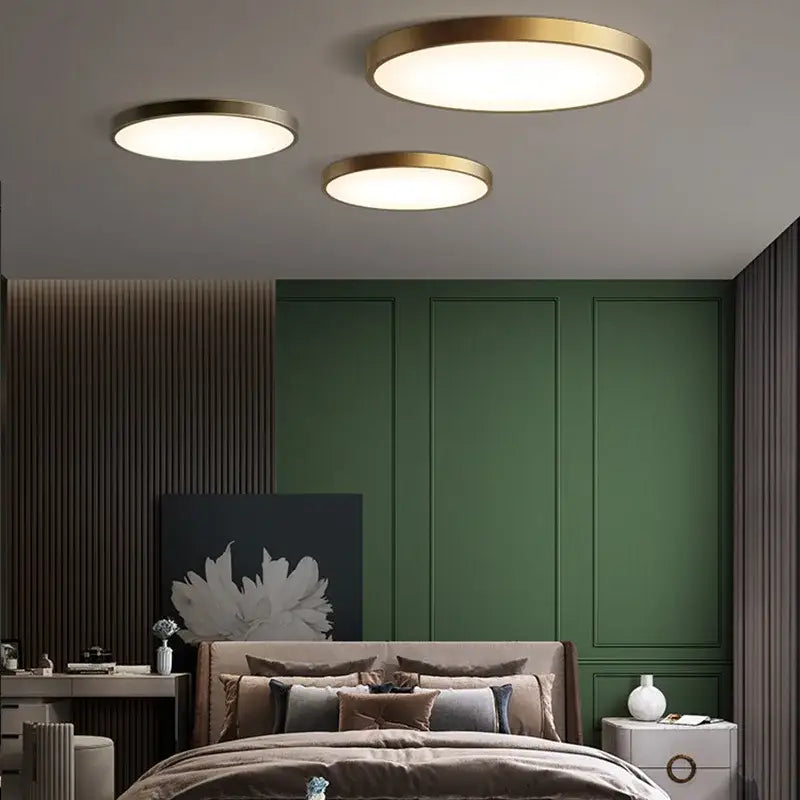 Three modern circular copper ceiling lamps with brushed brass finish and soft white frosted glass illumination for bedroom