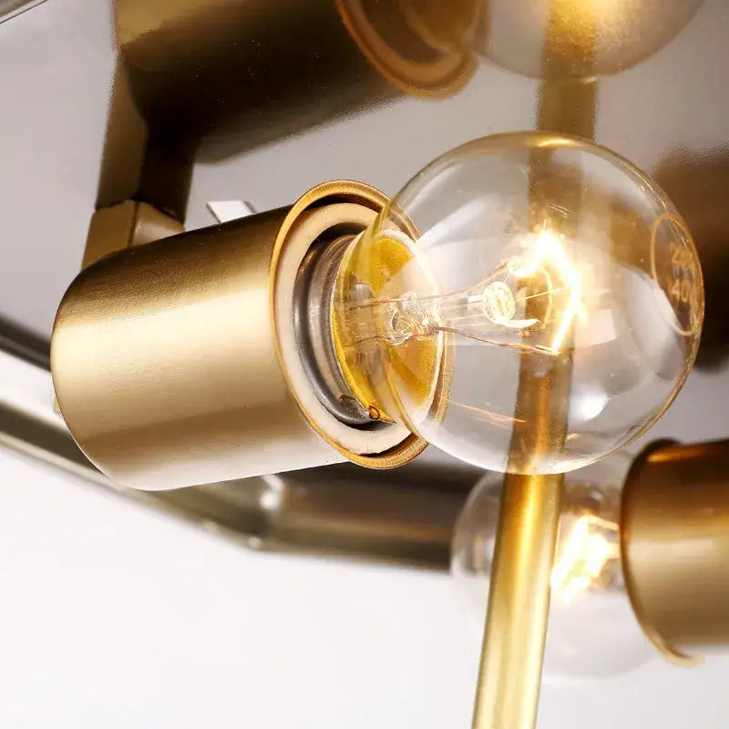 A glowing amber filament bulb in a brushed brass socket of a retro brass octagonal copper ceiling lamp for living room use