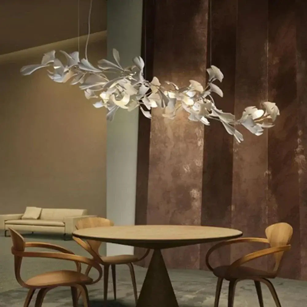 White ginkgo leaf chandelier lantern in modern organic design hangs above dining table as luxury leaf chandelier light