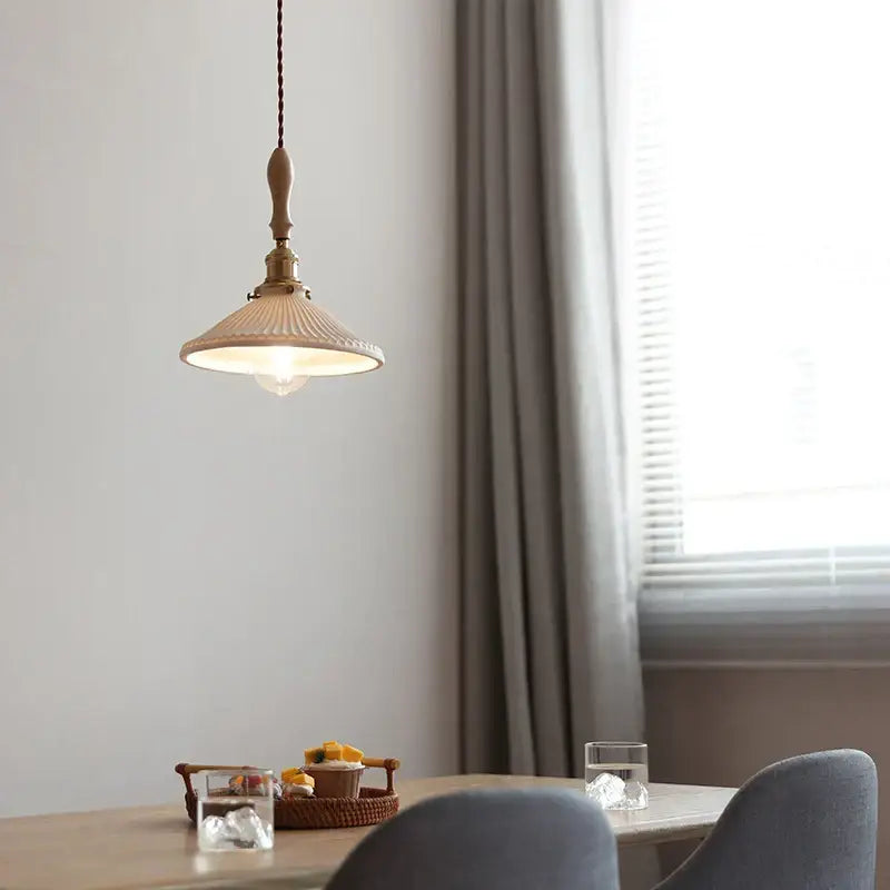 Vintage cream ceramic led pendant lamp with ribbed ceramic shade and brass accents hanging from twisted cord