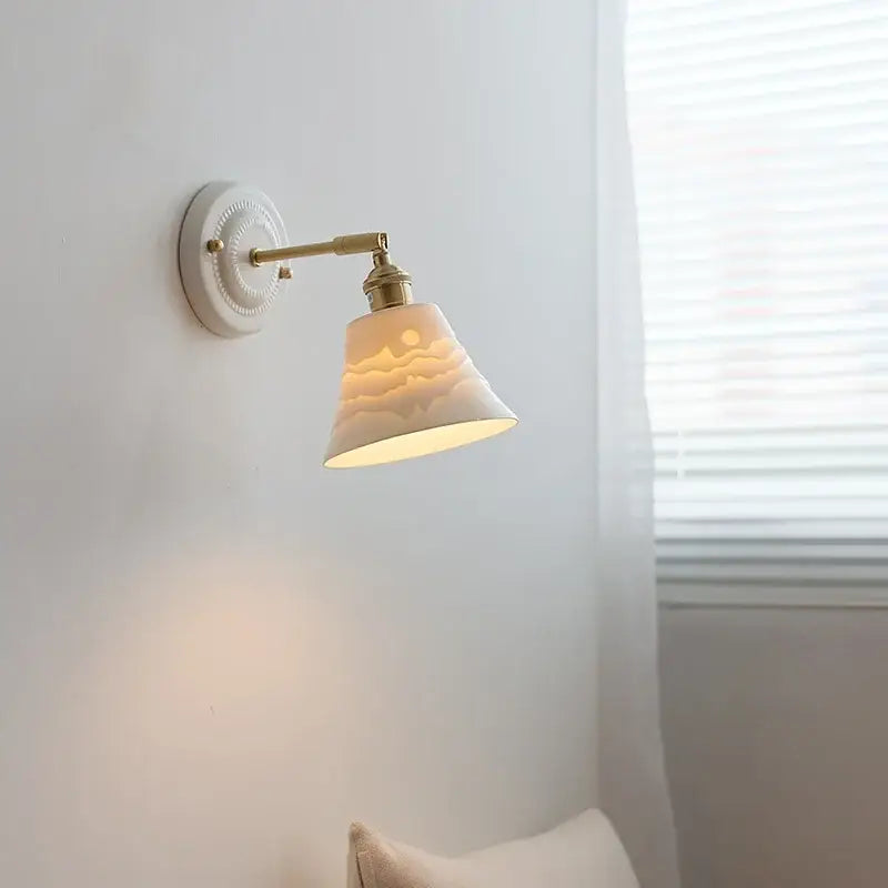 White and gold copper ceramic led wall lamp with brass arm and etched sun motif on conical off-white ceramic shade