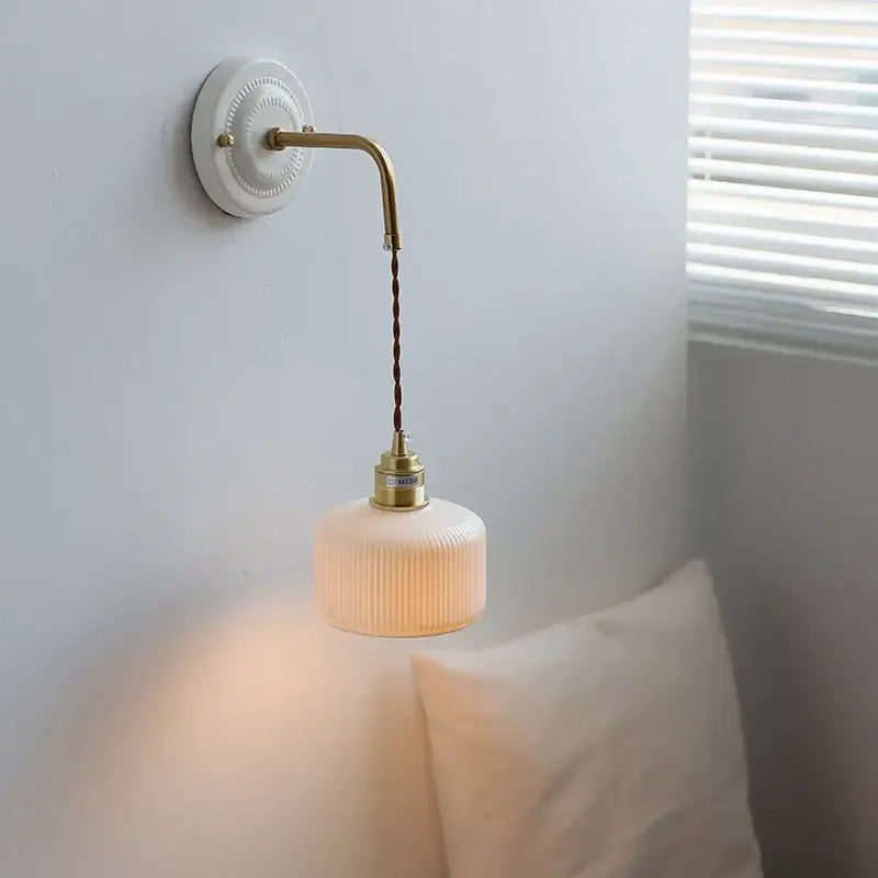 A warm cream-colored ribbed glass ceramic led wall light with vintage brass ceramic led metal arm and chain for living room