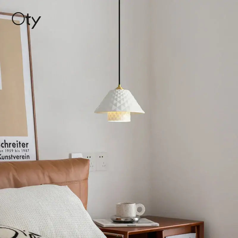 White geometric ceramic pendant light with gold-toned fixture and black cord for kitchen and dining room pendant lights