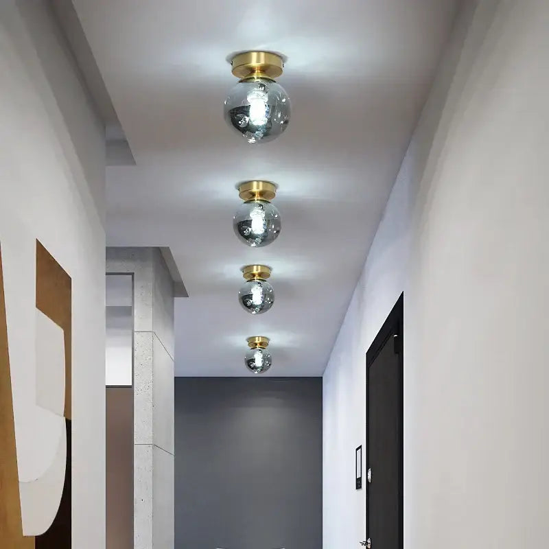 Four spherical mirrored glass ceiling lights with gold metal fixtures in a modern decorbites copper chandelier design