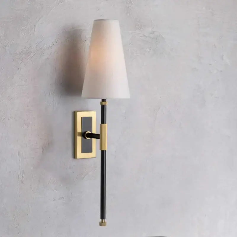 A sleek black and brass copper cloth led wall lamp with a tapered off-white fabric shade for bedroom reading