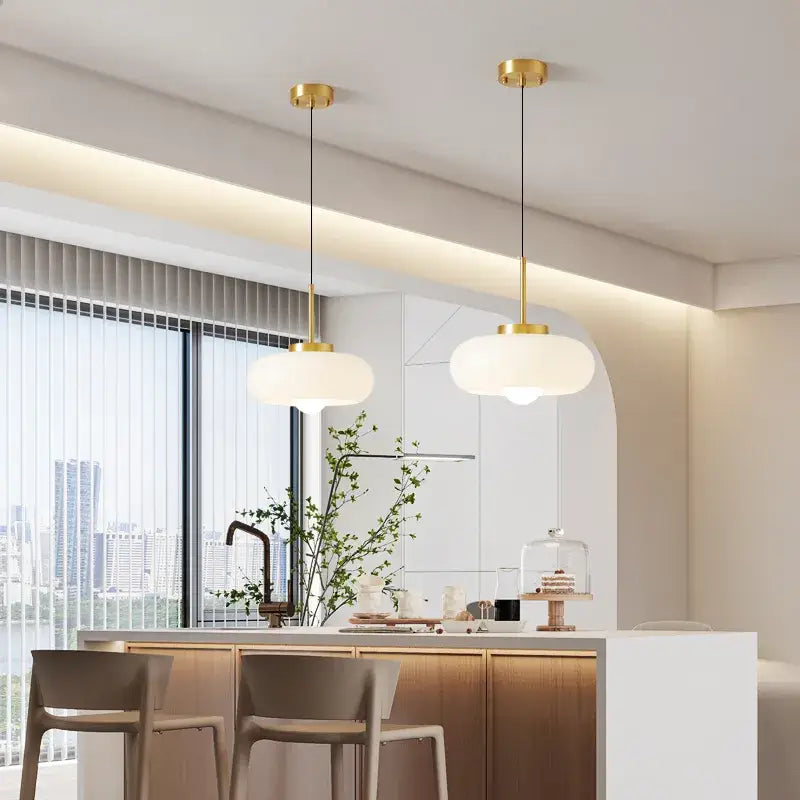 Two elegant white opal glass pendant lights with copper pendant light fixtures in a gold finish hanging from ceiling