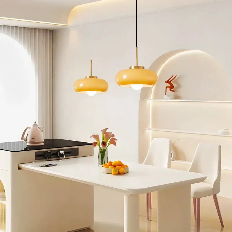 Two copper pendant lights with warm yellow glass shades hang above a white dining table from decorbites pendant light fixtures