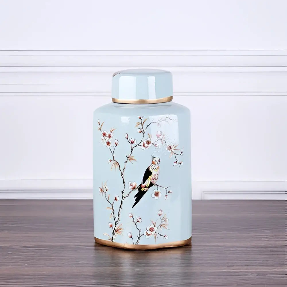 A light blue decorbites country ceramic tea canister with gold trim hand-painted cherry blossoms and perched bird design