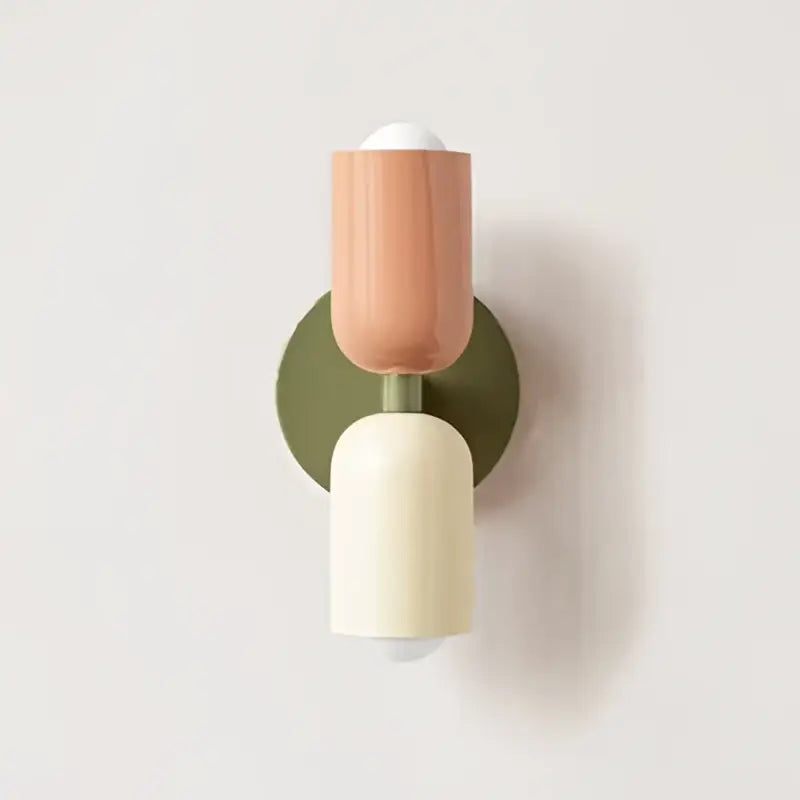 A decorbites cream double head wall lamp with olive matte base, peach and off-white cylindrical shades for bedroom use