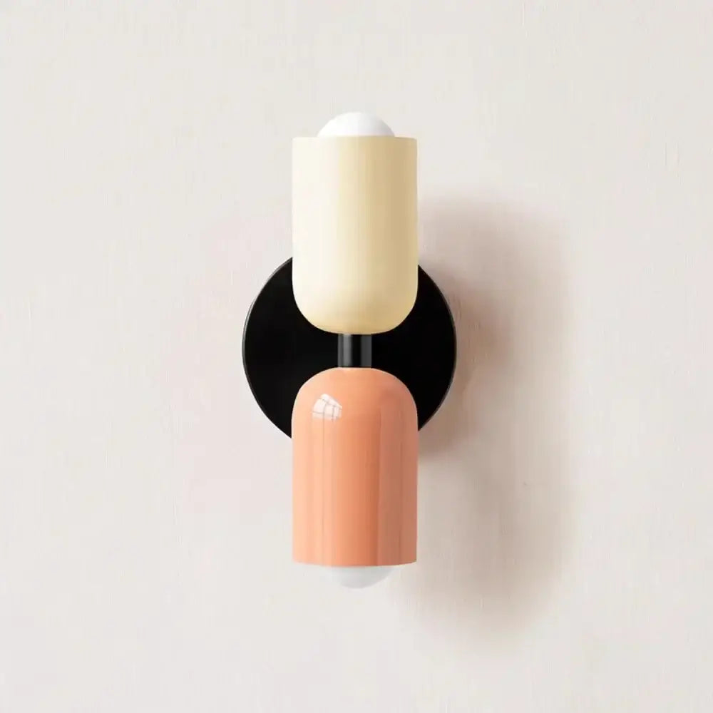 Cream double head wall lamp by Decorbites with peach cylindrical sconces and black circular base for bedroom use