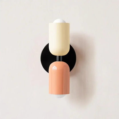 Cream double head wall lamp by Decorbites with peach cylindrical sconces and black circular base for bedroom use