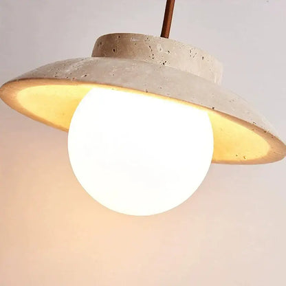 A modern decorbites cream stone pendant lamp with off-white textured concrete shade and glowing white bulb