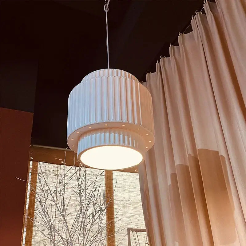 A modern decorbites cream wind led chandelier with a cream fluted cylindrical pendant light and warm glowing illumination