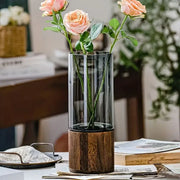 DecorBites™ creative retro glass living room vase with clear cylindrical glass and dark wood base holding peach roses
