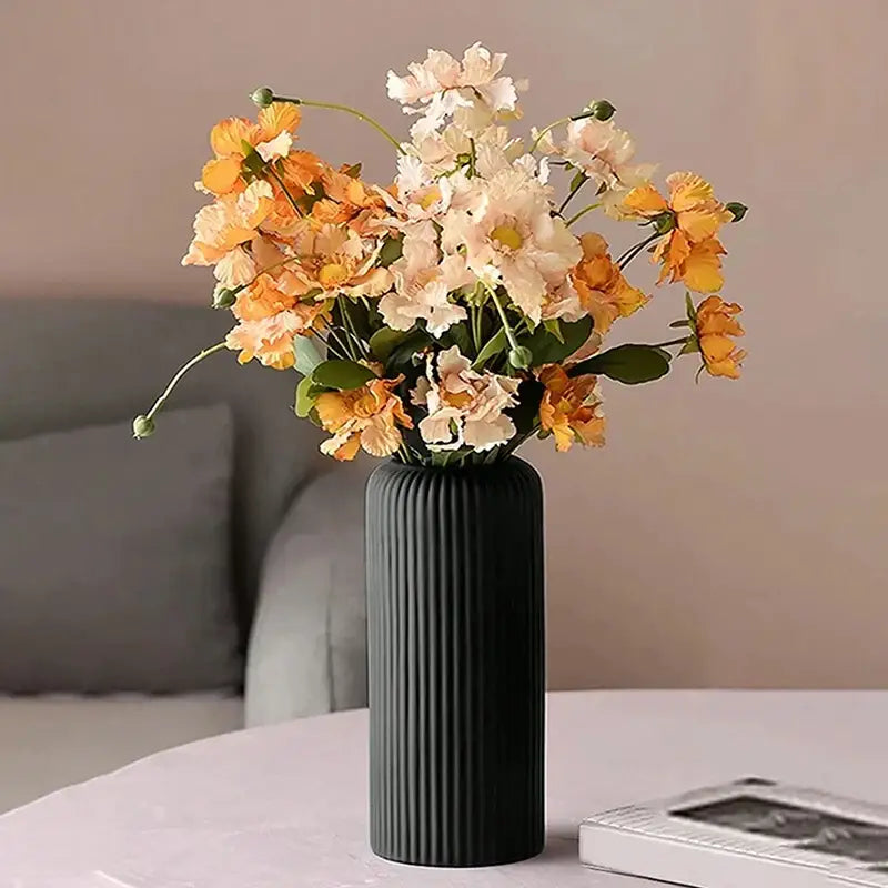 DecorBites™ black ribbed plastic flower vase holding orange and cream artificial floral arrangements
