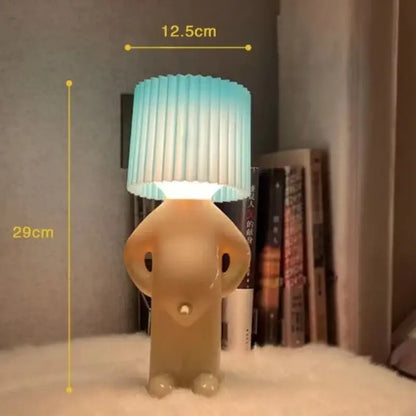 A creative table lamp by decorbites shaped like a beige translucent cartoon figure with a blue to white pleated shade