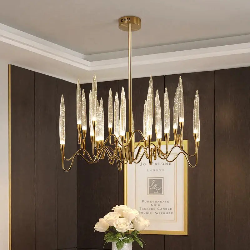 Gold-toned decorbites crystal branch chandelier with slender transparent glass arms resembling candle flames for dining room lighting