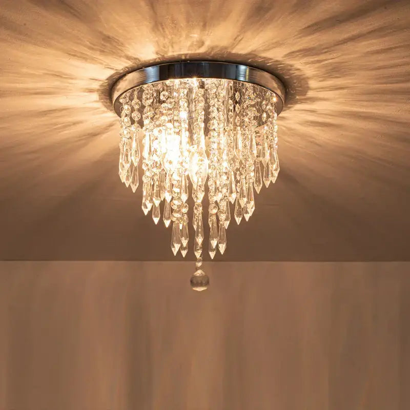DecorBites crystal ceiling light with chrome base and cascading glass prisms emitting warm light for elegant home decor