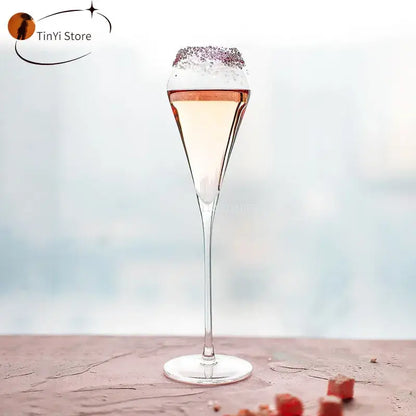 A decorbites crystal champagne flute filled with pale pink beverage and rimmed with sparkling sugar crystals