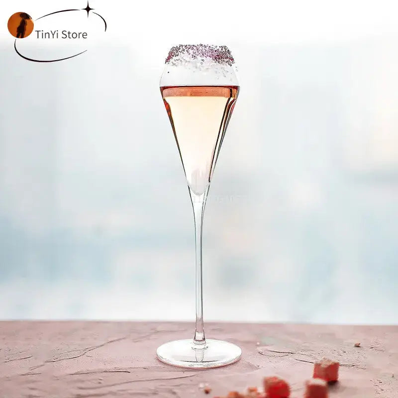A decorbites crystal champagne flute filled with pale pink beverage and rimmed with sparkling sugar crystals
