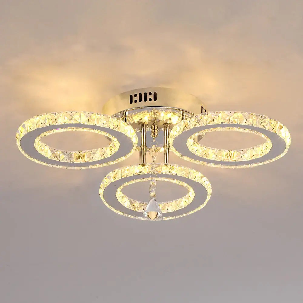 Gold-toned decorbites crystal chandelier with three illuminated circular tiers and central hanging crystal pendant for living room