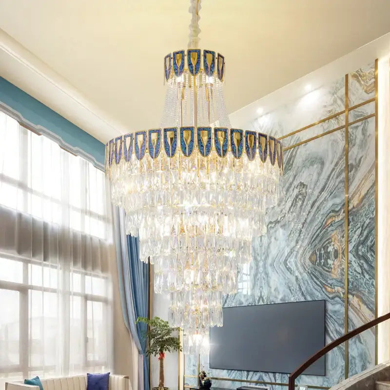 A multi-tiered decorbites crystal chandelier with blue and gold accents for duplex buildings and high-end restaurants