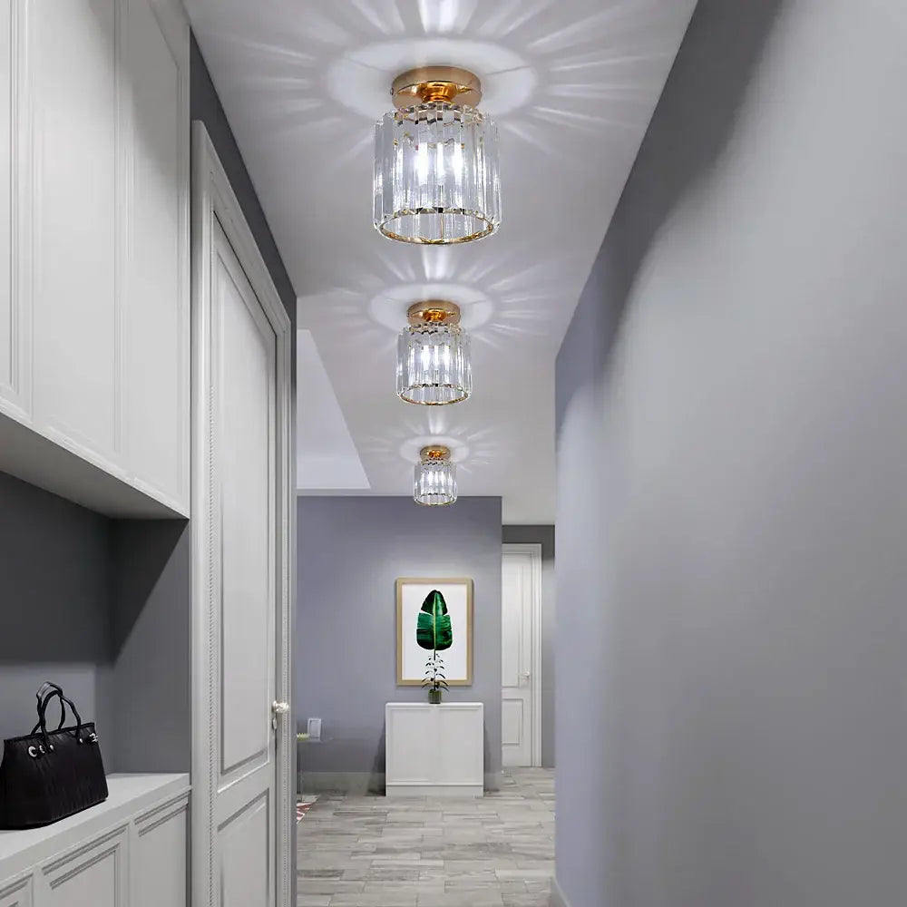 Three elegant gold-toned decorbites crystal chandelier ceiling lights with clear faceted prisms in a modern hallway