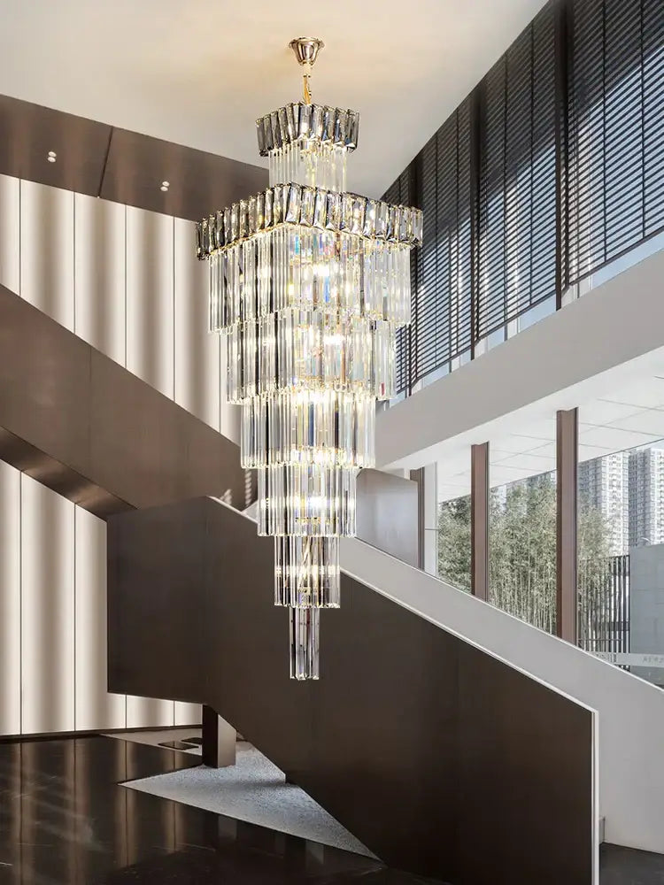 A decorbites crystal chandelier with a gold-toned mount and cascading rectangular prisms for duplex staircase lighting