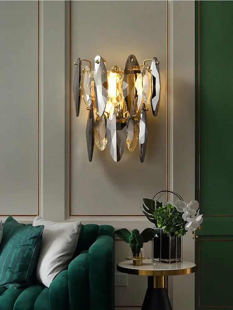 A modern decorbites crystal chandelier wall sconce with gold metal frame and cascading faceted crystal shards