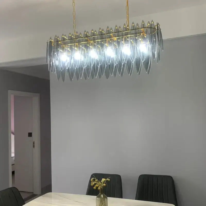 A modern decorbites crystal chandelier with gold-toned metal framing and cascading glass leaf shades for living spaces