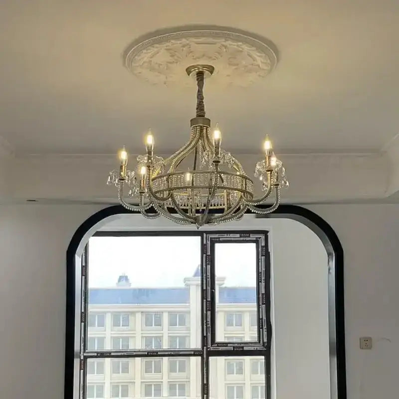 A gold-toned decorbites crystal chandelier with crystal droplets and candle-style bulbs for living room lighting