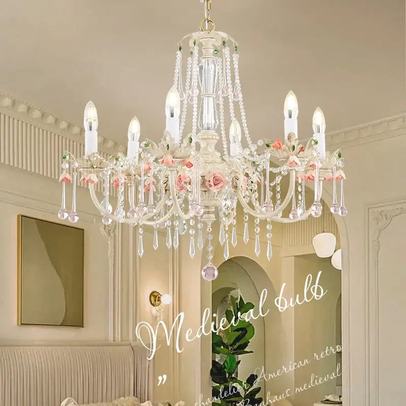 An ornate white decorbites crystal chandelier with crystal droplets and pink rose accents for elegant living rooms
