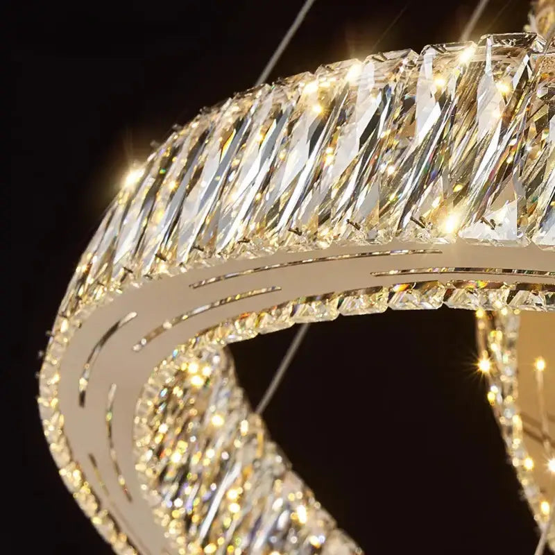 A modern decorbites crystal chandelier pendant light with a curved metallic frame and faceted crystal elements