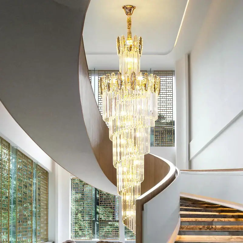 A decorbites crystal chandelier with gold-toned accents hangs elegantly above a spiral staircase in a minimalist duplex living room