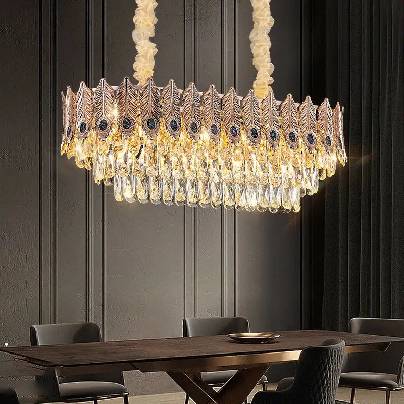Gold-toned decorbites crystal chandelier shaped like a peacock feather with cascading crystals and dark blue gemstones