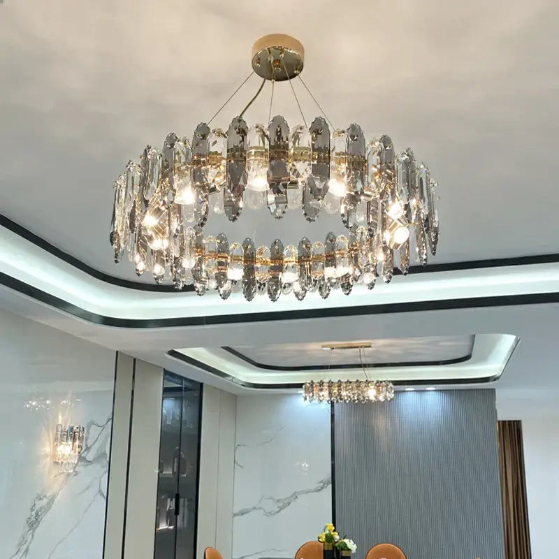 A two-tiered decorbites crystal chandelier with gold-toned metal and faceted glass pendant light elements for elegant spaces