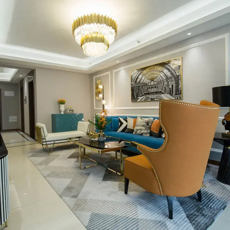 A plush orange wingback armchair with gold nailhead trim complements decorbites crystal chandelier pendant lights for living rooms