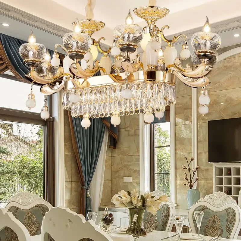 Opulent gold-toned decorbites crystal chandelier with cascading crystal droplets and frosted glass orbs for elegant interiors