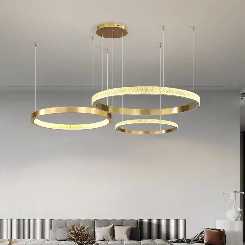 Modern gold-toned circular decorbites crystal chandelier with illuminated rings for luxury living and dining rooms