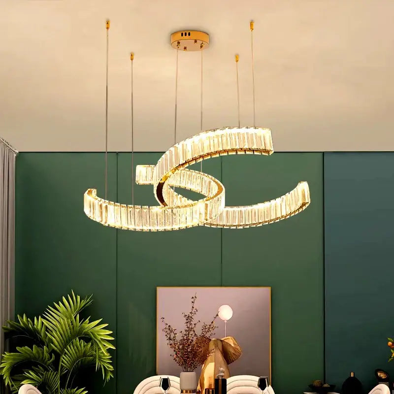 A modern gold-toned decorbites crystal chandelier with interlocking spiral rings and clear crystal accents for interior lighting