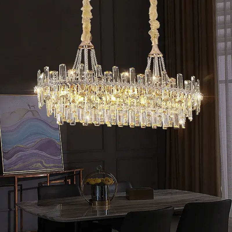 A luxurious decorbites crystal chandelier with cascading clear and golden prisms on cream metal chains for modern luxe homes