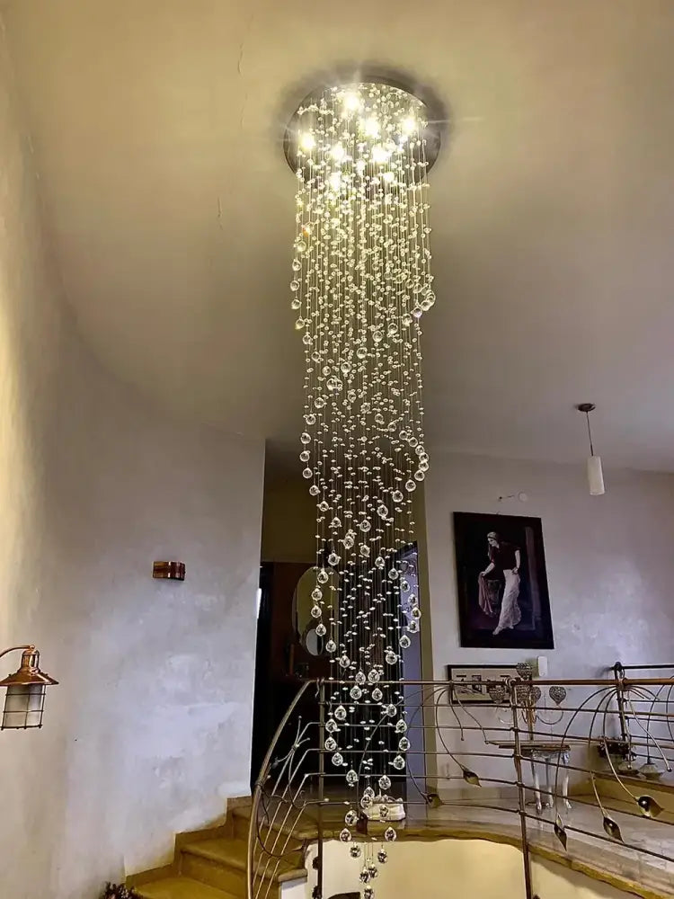 A decorbites crystal chandelier with clear crystal beads cascading from a circular metal frame emitting bright light
