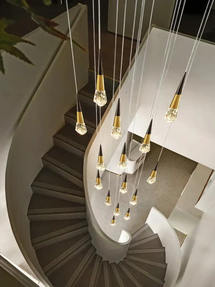 A decorbites crystal chandelier with gold-toned cone fixtures suspended above a curved staircase for dimming lighting