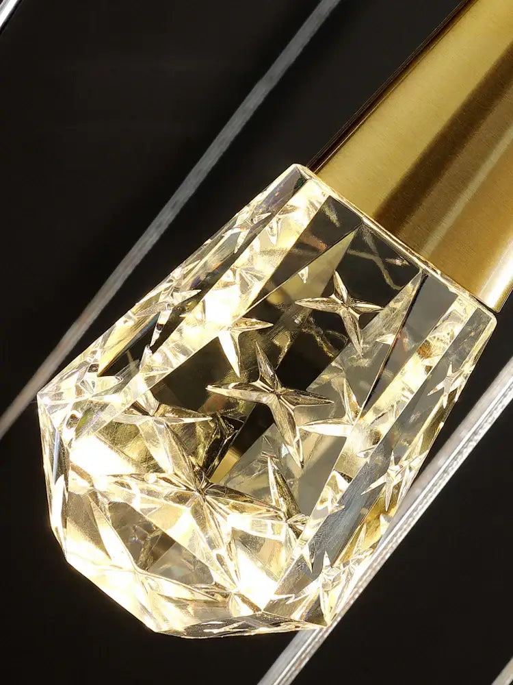 A faceted transparent decorbites crystal chandelier with star-shaped cutouts and a golden metallic cap for dimming lighting