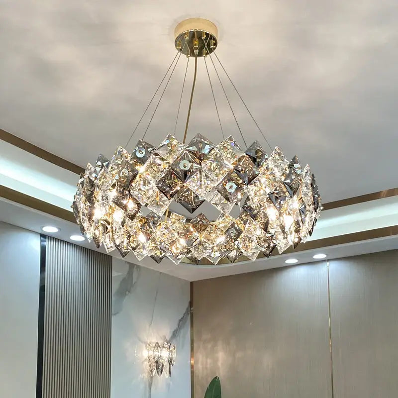 A decorbites crystal chandelier with faceted crystals in overlapping rings suspended by gold chains for elegant lighting