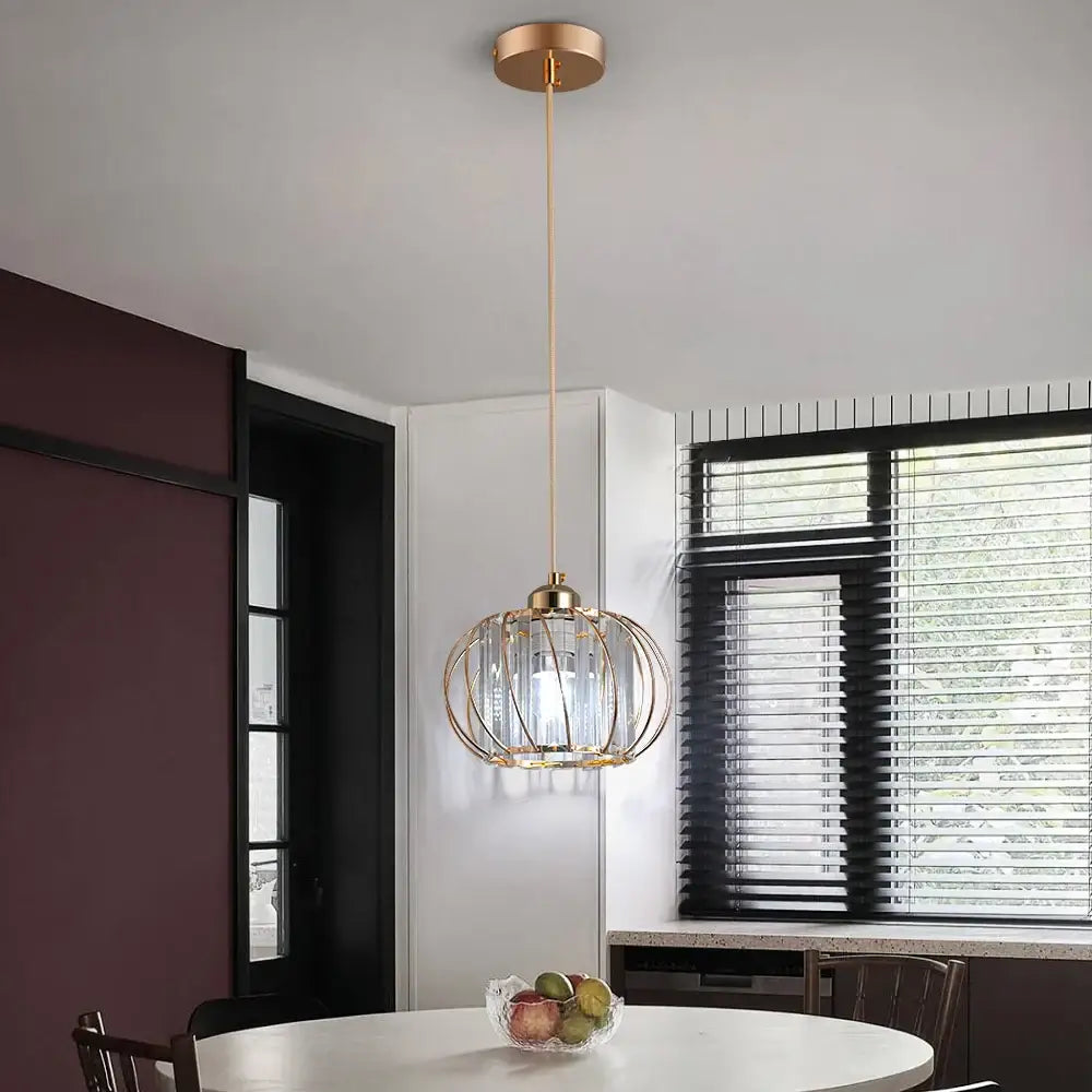 Gold-toned pendant light fixture with spherical cage design and clear glass panels for modern home décor