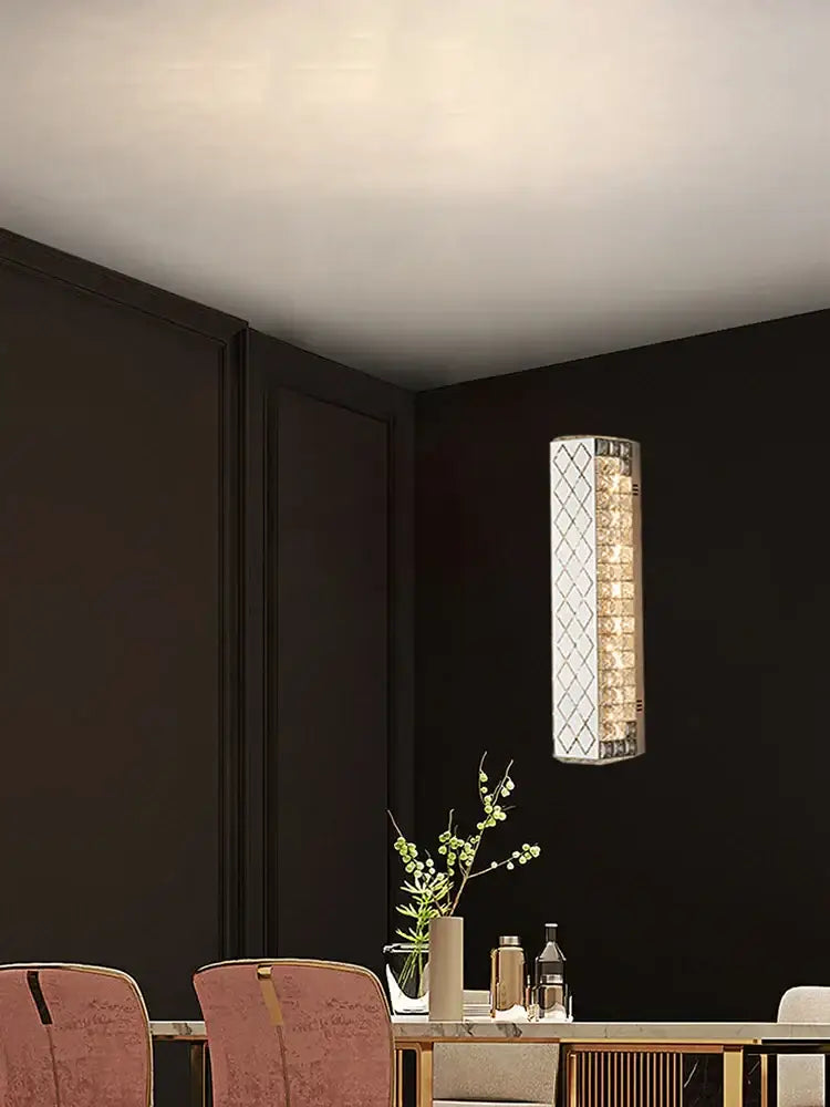 A sleek decorbites crystal chandelier wall sconce with clear and amber crystal elements in a metallic frame for dining rooms