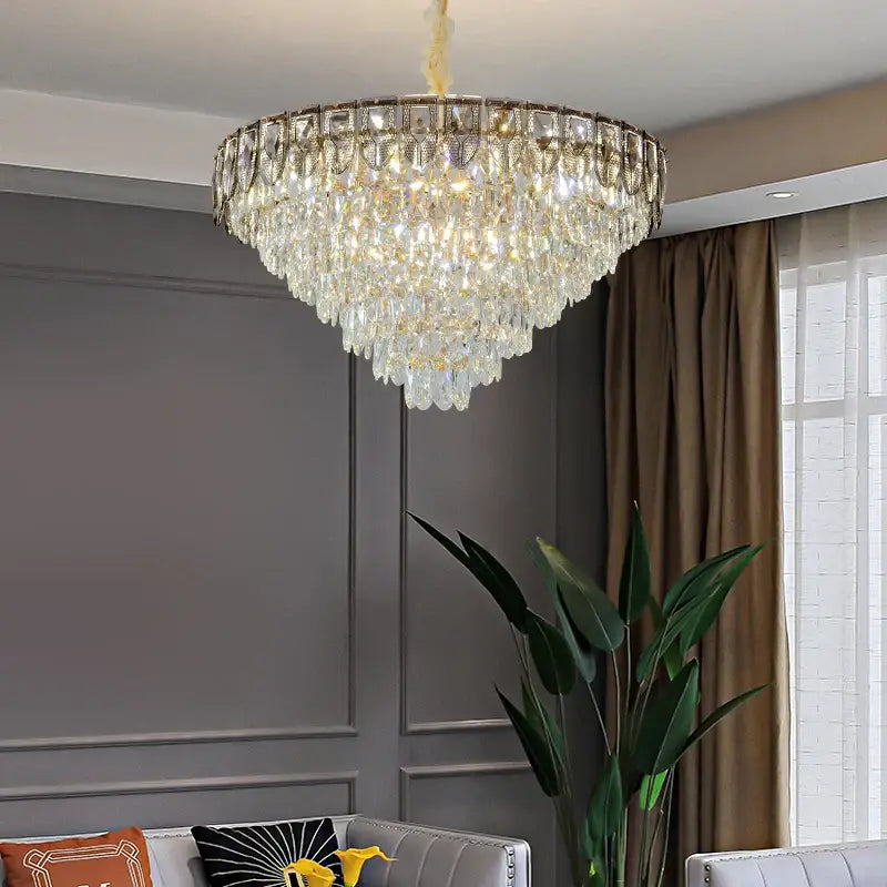 A multi-tiered decorbites crystal chandelier with gold metal frame and cascading clear crystals for luxury living rooms