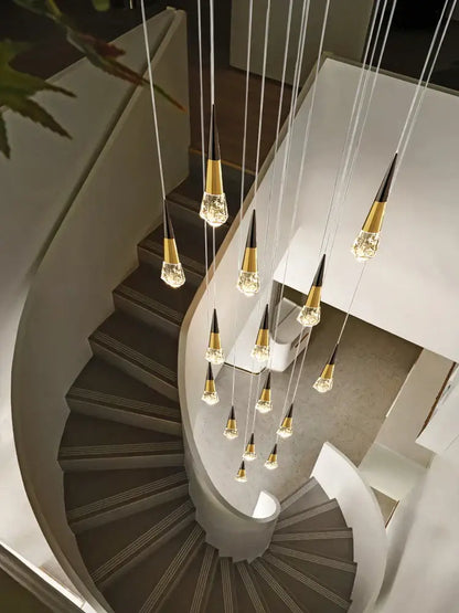 A decorbites crystal chandelier led with gold-toned cone fixtures suspended above a curved staircase for elegant spaces