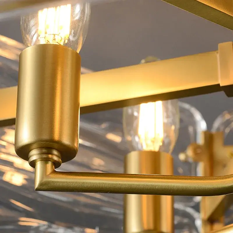 Gold-toned metal arm of decorbites crystal chandelier lighting with cylindrical socket and exposed filament bulb